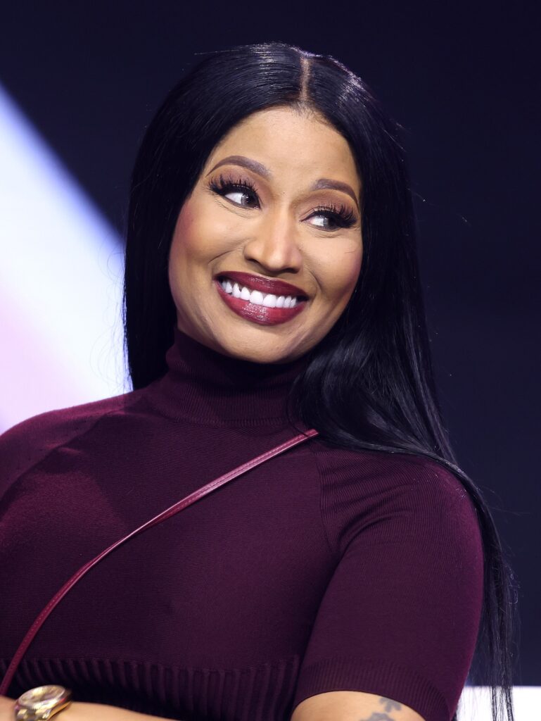Nicki Minaj smiling on stage at AmericaFest in Phoenix, December 2025
